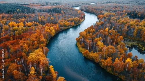 The image shows an aerial view of a river flowing through a forest in autumn