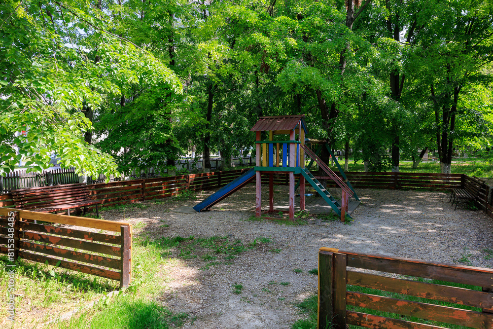 A playground with wooden fence and a wooden play structure A playground with wooden fence and a wooden play structure