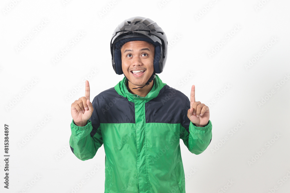 Portrait of Asian online taxi driver wearing green jacket and helmet pointing at empty space with finger. Isolated image on white background Portrait of Asian online taxi driver wearing green jacket and helmet pointing at empty space with finger. Isolated image on white background