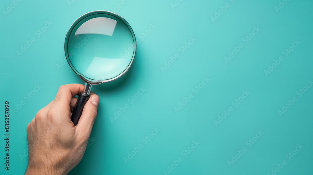 Magnifying glass in hand, isolated on blue background with copy space Magnifying glass in hand, isolated on blue background with copy space
