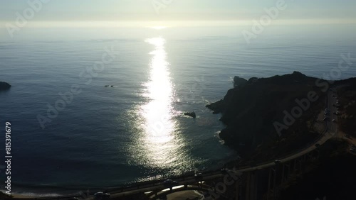 4K drone footage. Panoramic scenic view from above of the old historic Bixby Creek Bridge with the colorful Pacific Ocean as a backdrop. The sun is reflected in the waves in the background. Big Sur