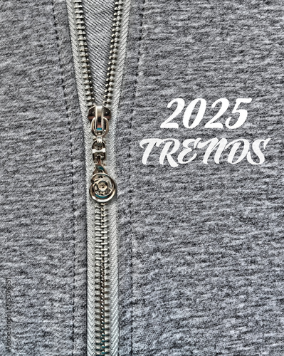 2025 Trends , text on gray textile. Fashion industry. Decorative silver slider  in zipper on textile gray melange woolen  clothes . 