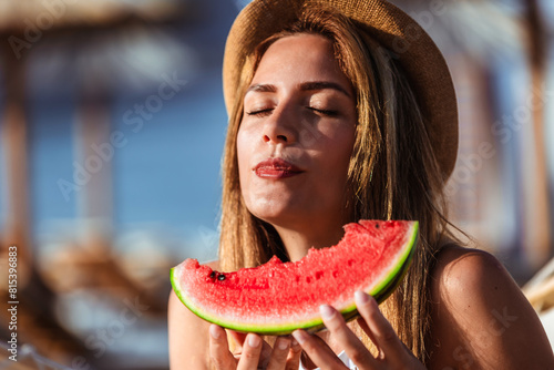 Young beautiful woman eating juicy watermelon on the beach.