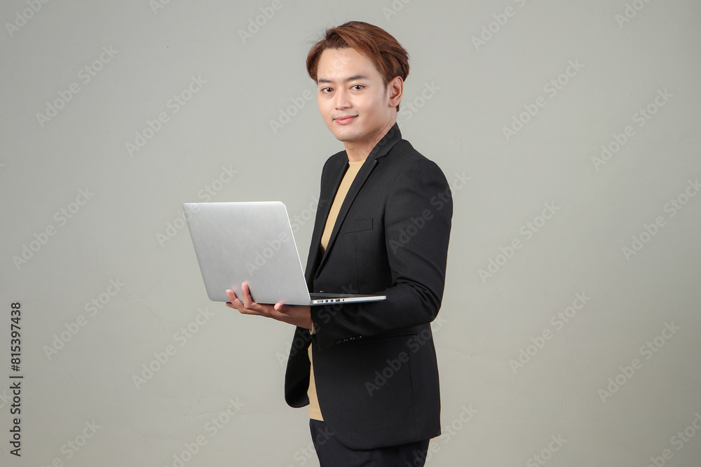 portrait of happy asian businessman holding laptop computer wearing suit on isolated background portrait of happy asian businessman holding laptop computer wearing suit on isolated background