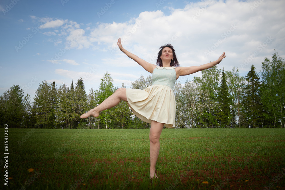 A beautiful young funny woman does sports or dance exercises in nature. A girl at a photo shoot in the landscape in spring or summer A beautiful young funny woman does sports or dance exercises in nature. A girl at a photo shoot in the landscape in spring or summer