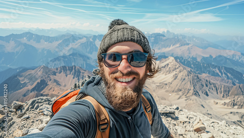 Young man taking a selfie on a mountain summit with panoramic view. © lenblr