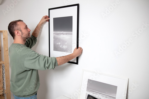 Man hanging pictures on the wall.