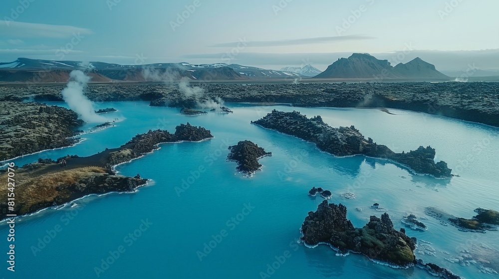 Aerial view of the Blue Lagoon in Iceland, with its milky blue geothermal waters surrounded by black lava fields and distant mountains.     