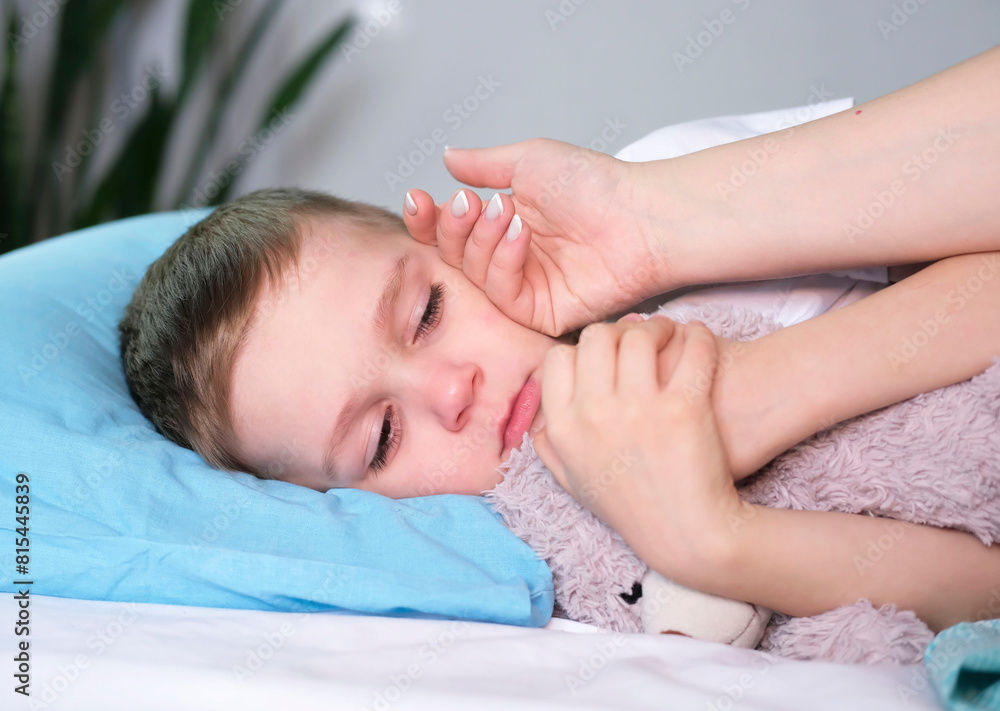Concerned mother checks temperature of sick child lying in bed. Preschooler suffers from fever from coronavirus or flu. Concept of treatment, health and infection of children. Concerned mother checks temperature of sick child lying in bed. Preschooler suffers from fever from coronavirus or flu. Concept of treatment, health and infection of children.