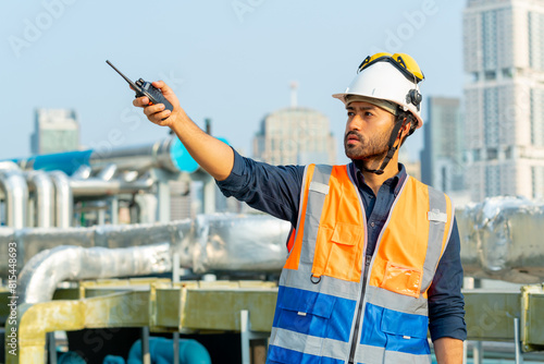 Portrait of Professional Asian man engineer in safety uniform working outdoor at construction site building rooftop. Architecture technician inspector inspect building exterior structure system.