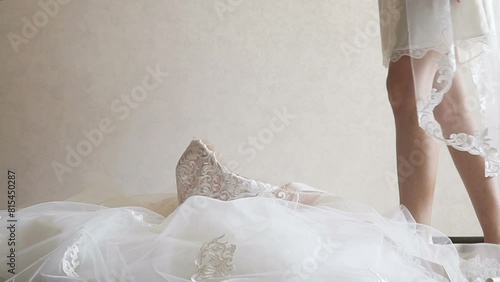 The bride steps barefoot into her wedding dress. The bride getting ready in the morning. Wedding day. Women's feet. Toes touch the floor.