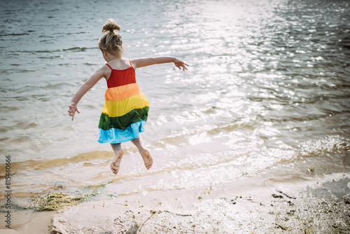 Young child joyfully jumping near lake shore