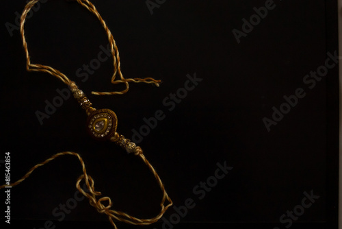 Happy Raksha Bandhan. A rakhi thread made of gold on a black background. Macro. Copyspace. Brother-sister bond photo