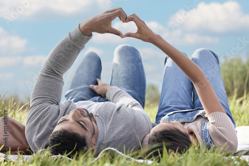 Photography Grass, couple or picnic with heart hands relaxing in park for romantic date, love or celebration together