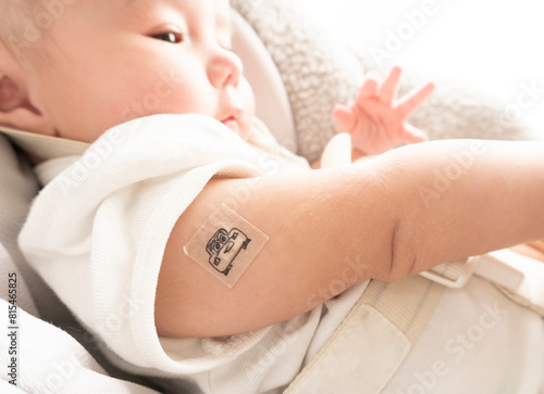 Band-aid with character on it on baby's right arm with red skin after vaccination
