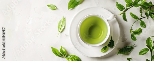 white cup filled with green tea, surrounded by scattered fresh leaves on a bright white background.