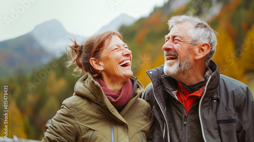 Elderly man and woman laugh joyfully against a mountain backdrop