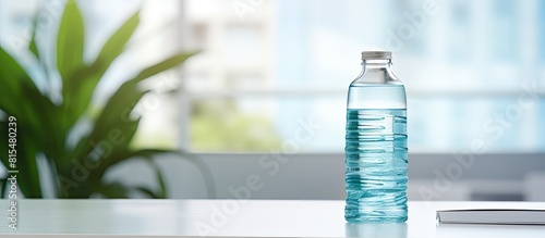 An image of a plastic bottle filled with clear water stands on top of a desk in a modern office The background showcases the interior of the office reflecting the concept of working both on site and photo