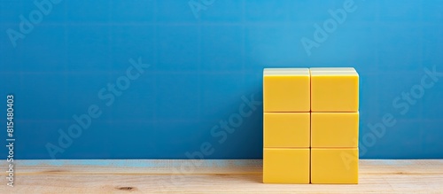 A yellow cube calendar is placed on a blue wooden surface providing ample copy space for additional content © HN Works