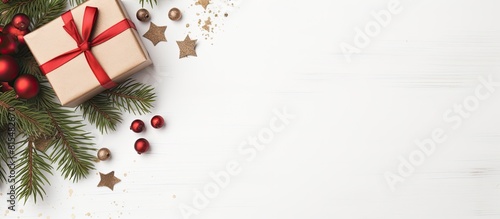 A Christmas gift box adorned with fir and decorations is showcased on a white background The image offers ample copy space and is captured from a top down perspective creating a flat lay composition