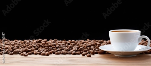 A copy space image featuring a white cup filled with coffee and surrounded by coffee beans