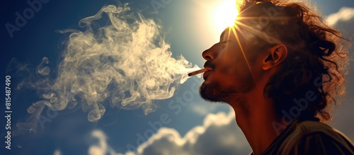 A man is seen holding a burning marijuana joint against the backdrop of a serene sky and a radiant sun The image also includes a cigarette emitting smoke located at the top right corner providing amp
