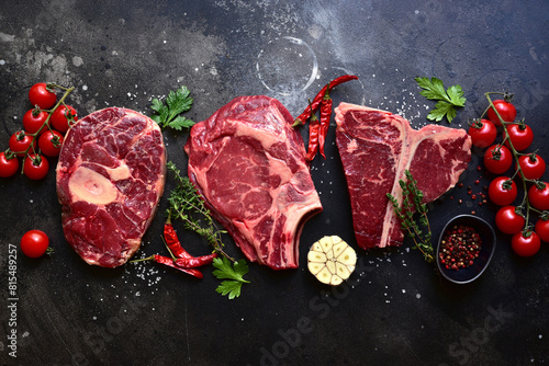 Raw organic marbled beef steaks : ossobuko, rib eye ( cowboy ) , T - bone. Top view with copy space.