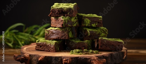 A copy space image on a wooden board features a stack of deliciously healthy matcha and dark chocolate brownies