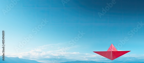 A panoramic shot captures a leadership concept with a top view of a red paper plane on a blue background offering ample copy space