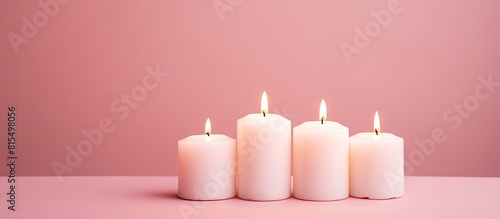 A flat lay image features three white wax candles placed on a pink background leaving ample copy space