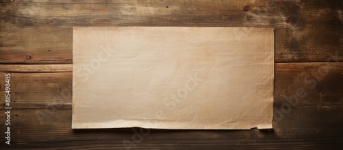 A worn out sheet of paper rests on a rustic wooden surface creating a nostalgic and vintage atmosphere in the copy space image