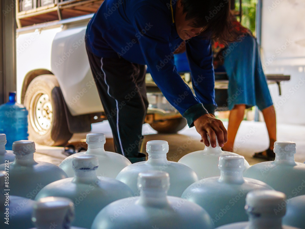 Workers lift drinking water .clear and clean in white plastic gallon into the back of a transport truck purified drinking water inside the production line to prepare for sale. Water drink factory Workers lift drinking water .clear and clean in white plastic gallon into the back of a transport truck purified drinking water inside the production line to prepare for sale. Water drink factory