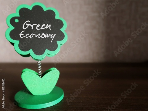 Mini tree chalkboard with text Green Economy, refers to economy aims at reducing environmental risks and ecological scarcities, and sustainable development