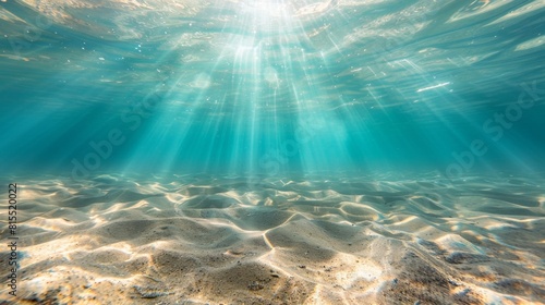 Underwater view of sunbeams filtering through crystal-clear water  illuminating a sandy ocean floor