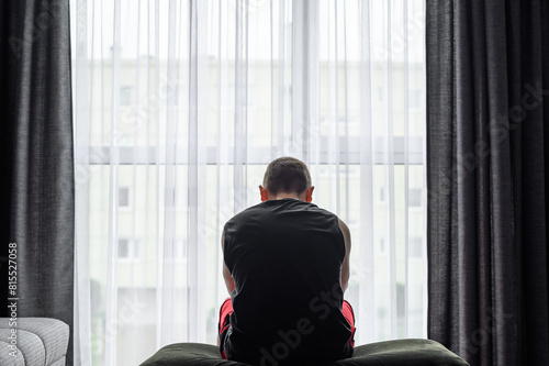 Mężczyzna z depresją siedzi w domu i wygląda załamany przez okno  photo