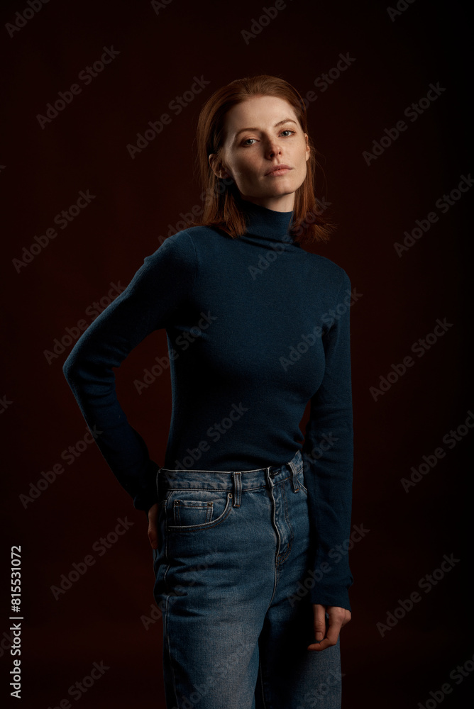 A beautiful red-haired girl with freckles poses in the studio on a brown background. Grain effect used A beautiful red-haired girl with freckles poses in the studio on a brown background. Grain effect used