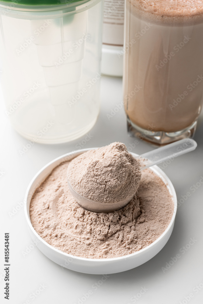 Whey protein powder in a measuring scoop and protein drink cocktail in a glass Whey protein powder in a measuring scoop and protein drink cocktail in a glass