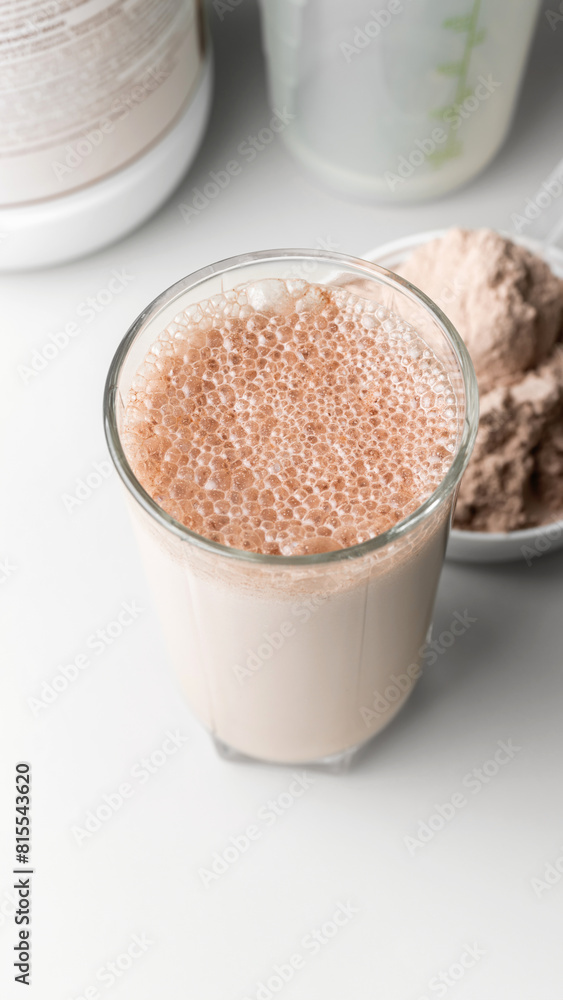 Protein drink cocktail in a glass and whey protein powder in a measuring scoop Protein drink cocktail in a glass and whey protein powder in a measuring scoop