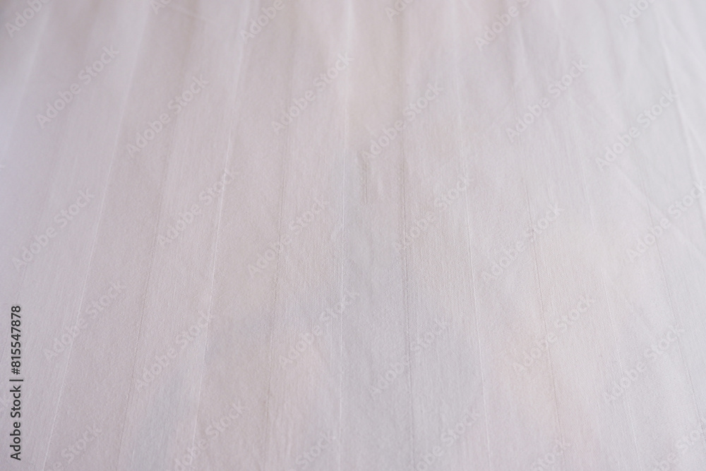 Obraz premium White bed sheet background. Close-up bedding sheet texture. White background for fibers and textiles, bedroom, cotton, hotel, and mattress. Abstract white fabric background with copy space.