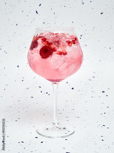 Close-up of Refreshing Pink Gin Tonic with Berries against a speckled background