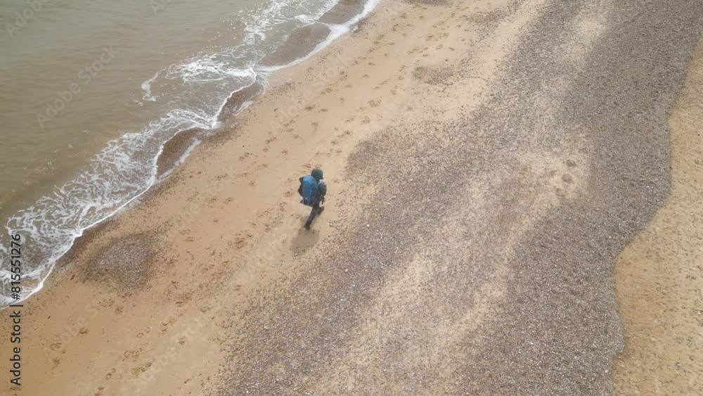 Aerial view of a tourist with backpack walking on Kessingland Beach in Suffolk, England. Aerial view of a tourist with backpack walking on Kessingland Beach in Suffolk, England.