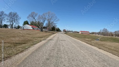 POV - Driving on country road past cemetery, barn, and empty fields in early spring in the Midwest; making multiple turns to stop in front of a garbage binconcepts of country life and agriculture photo