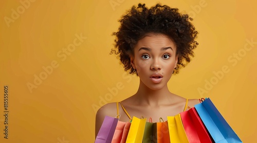 A stylish woman holding multiple shopping bags against a vibrant yellow backdrop photo