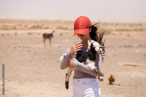 Young girl holding a baby goat in the desert of South Morocco
