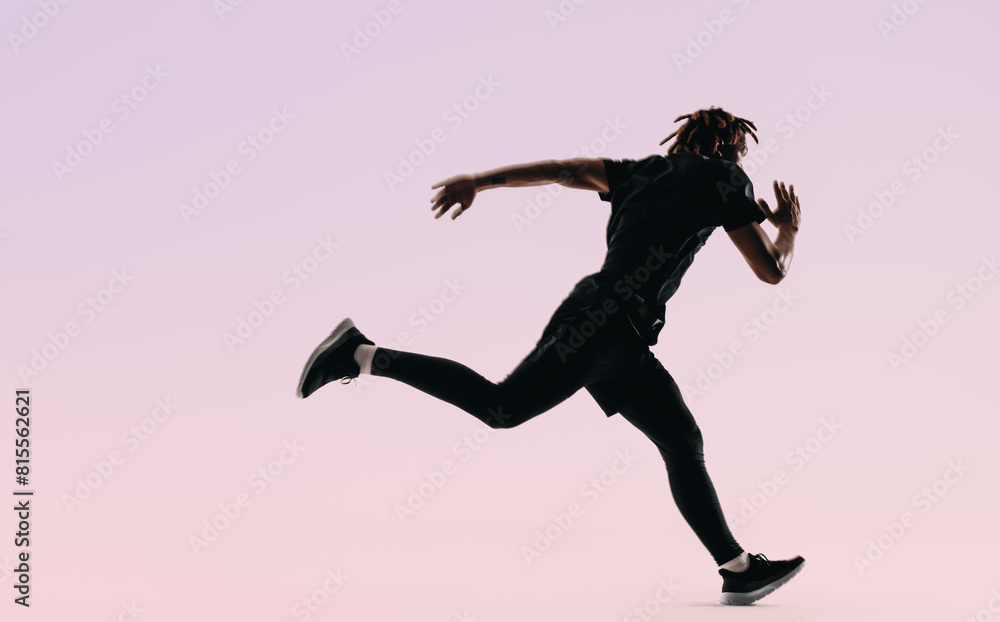 Silhouette of a fit athlete sprinting in a studio with a pink background Silhouette of a fit athlete sprinting in a studio with a pink background
