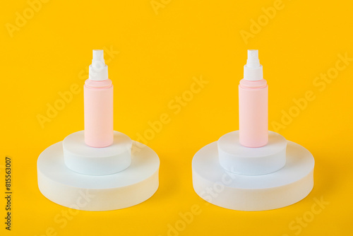 Cosmetic pink bottle, bottle, lotion or serum with stylish props on yellow background. 