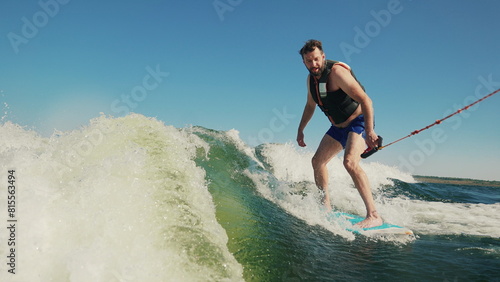 A man wakeboards after a boat. Fun on the water during the hot summer on the lake. Wakeboarding. Summer sports on a lake with blue water. Wakeboarding behind a motor boat. Active lifestyle concept. © Volodymyr