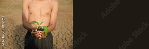 Hand man planting tree to restore and change earth and environment. Boy's hand holds seedling covered with dirt soil on dry and crack ground. Drought and El Nino condition concept-banner image.