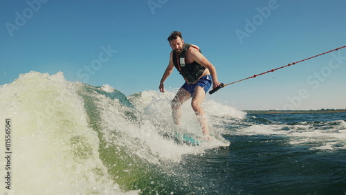 A man wakeboards after a boat. Fun on the water during the hot summer on the lake. Wakeboarding. Summer sports on a lake with blue water. Wakeboarding behind a motor boat. Active lifestyle concept.