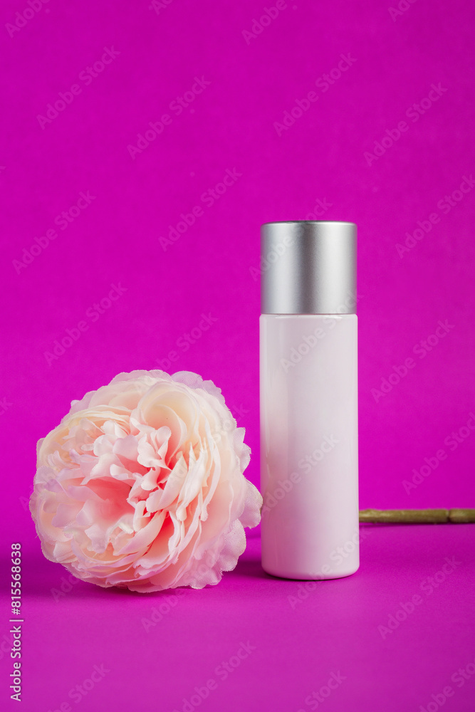 Plastic white tube for cream or lotion. Skin care or sunscreen cosmetic with fake flowers on purple background. Plastic white tube for cream or lotion. Skin care or sunscreen cosmetic with fake flowers on purple background.
